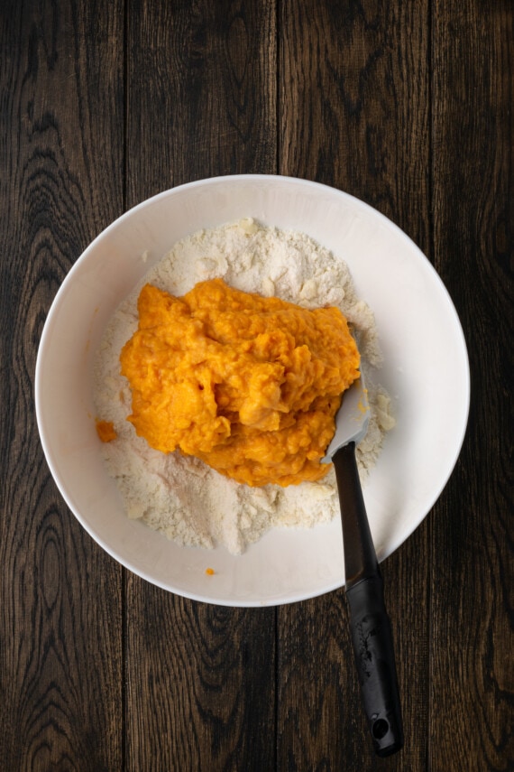 Puré de camote agregado a los ingredientes de la masa de galletas en un tazón blanco.