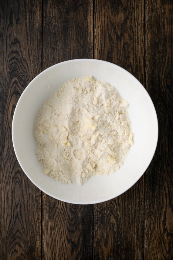 Mantequilla desmenuzada con harina para masa de galletas en un tazón blanco.