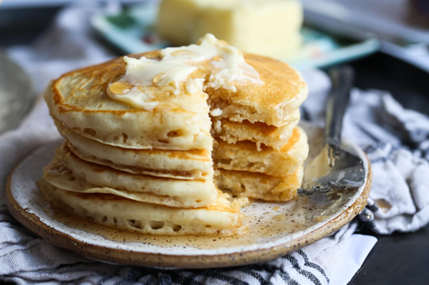 Panqueques apilados en un plato con mantequilla y falta una rebanada