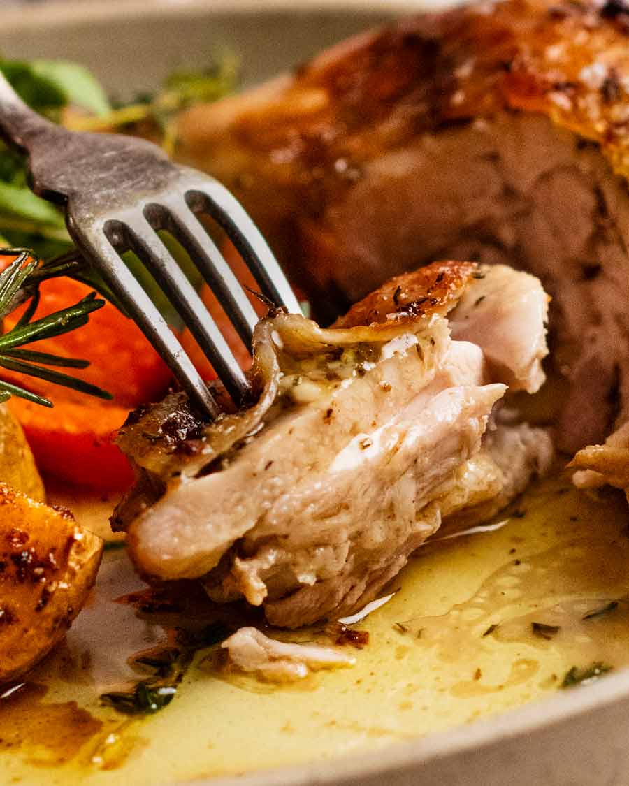 Cerca de la horquilla recogiendo un trozo de pollo con mantequilla de ajo y hierbas Marylands