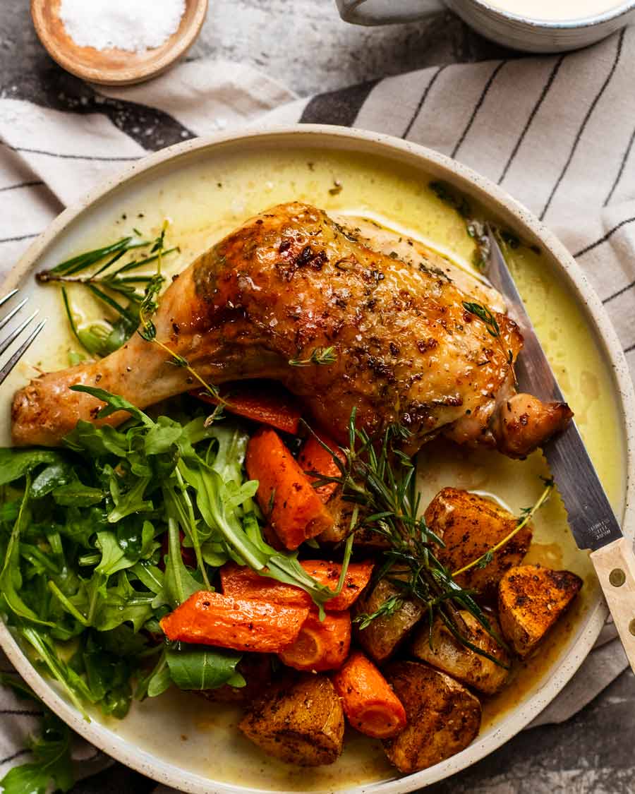 Marylands de pollo con mantequilla de ajo y hierbas en un plato con verduras asadas y ensalada fresca