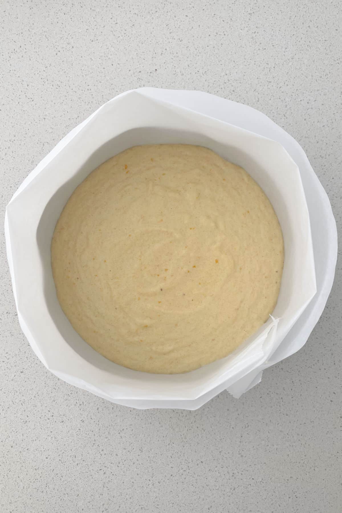 La masa de bizcocho de naranja entera se vierte en un molde para bizcocho forrado.
