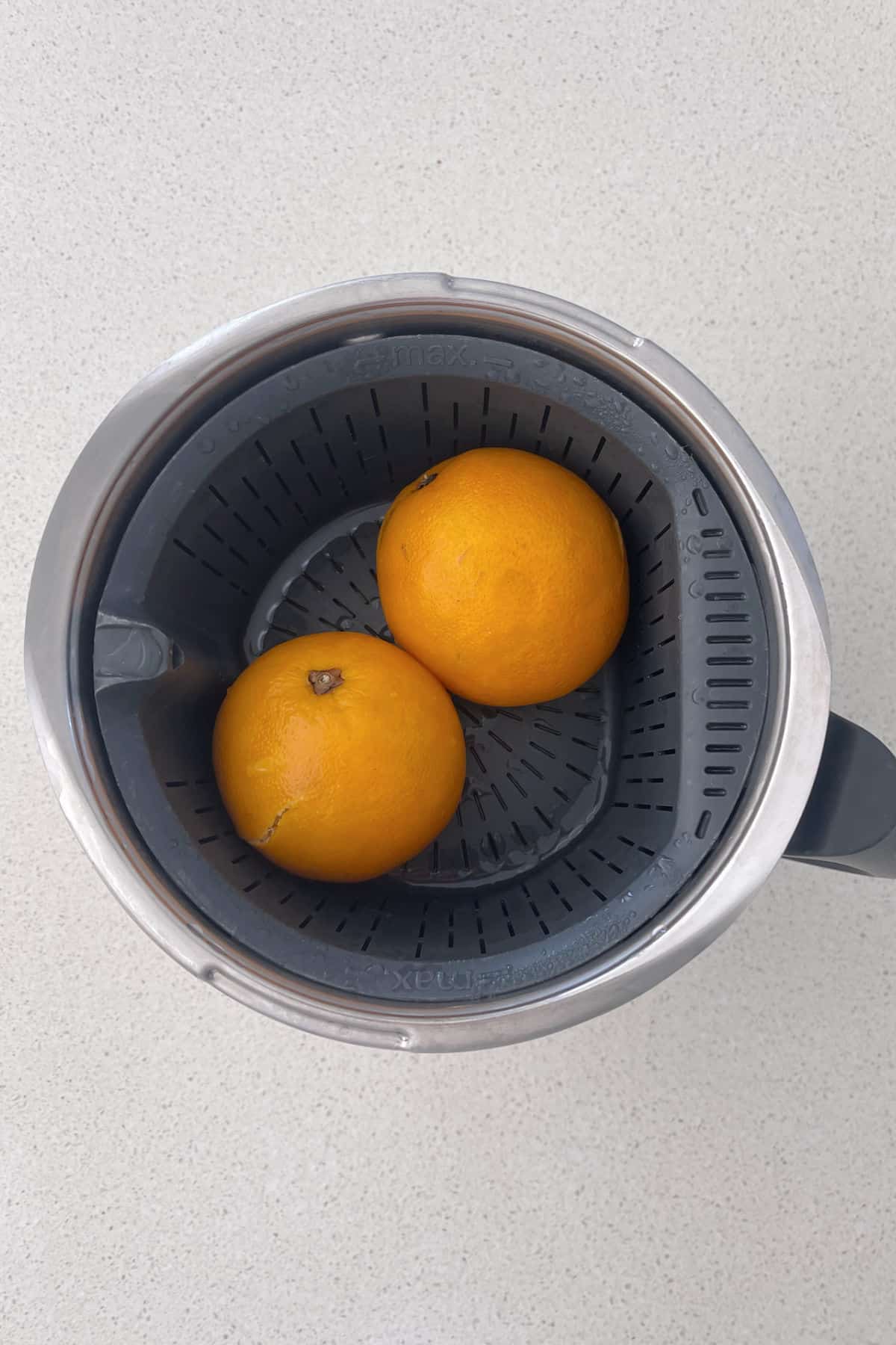 Dos naranjas cocidas sentadas en una Thermomix humeante.