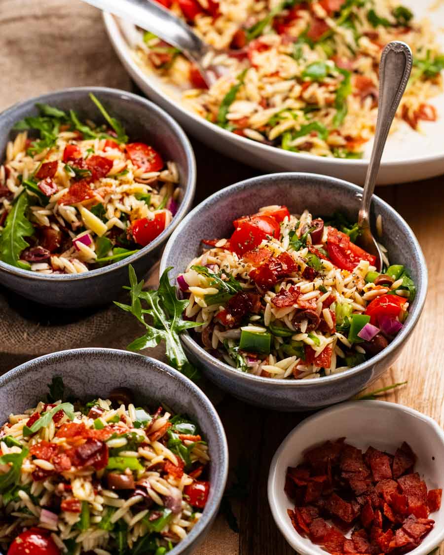 Ensalada italiana de risoni/ orzo con trocitos de salami crujiente en tazones listos para comer