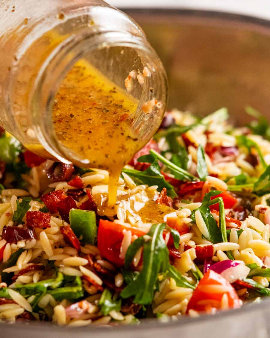 Vierta el aderezo sobre la ensalada italiana de risoni/orzo con trocitos de salami crujiente