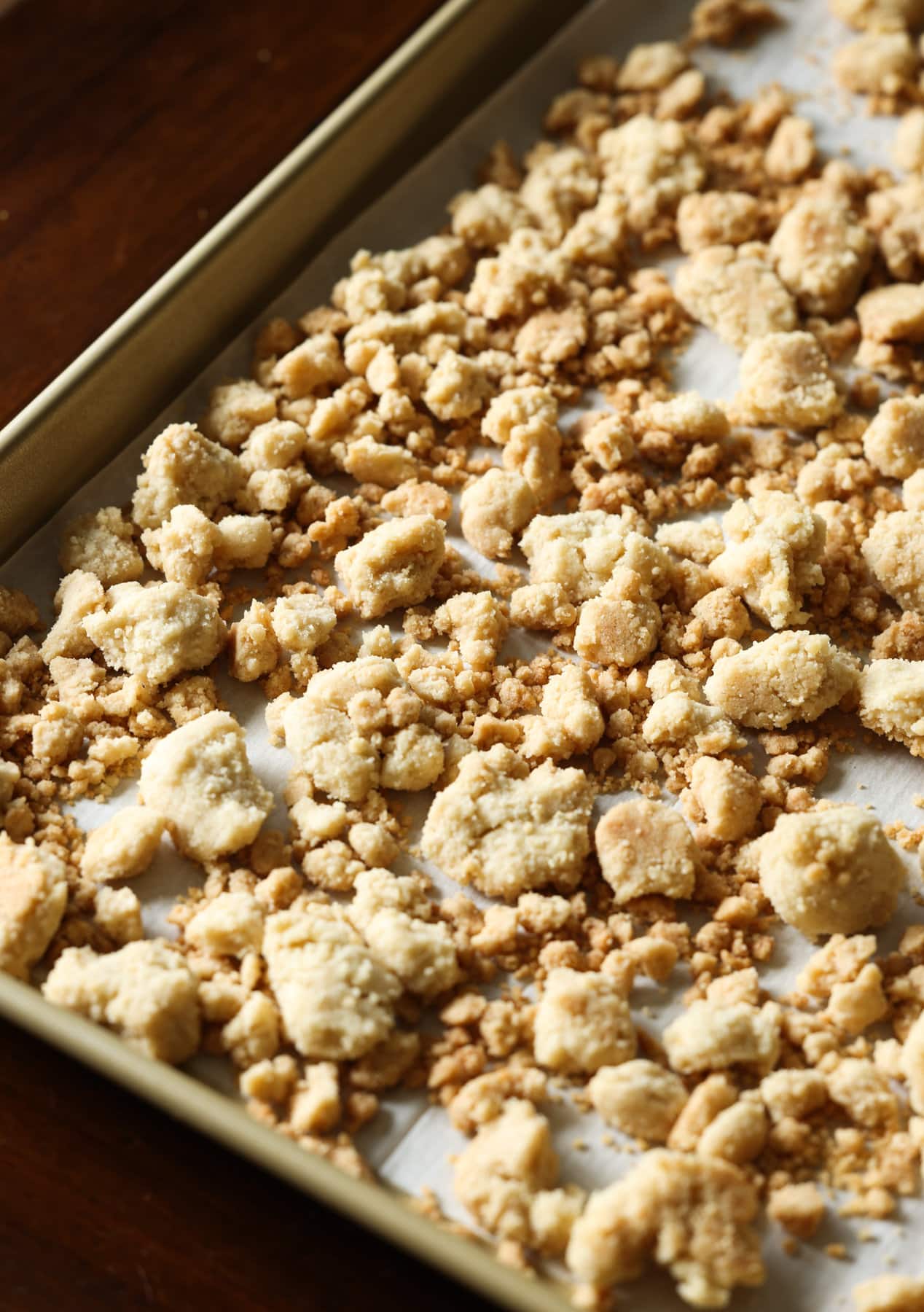 Streusel Topping, también conocido como Crumb Topping, es muy fácil de hacer y se puede usar en muchos productos horneados diferentes, desde muffins y panes hasta pasteles y tartas, ¡o se hornea solo y se usa como una cobertura crujiente de mantequilla! Crunchy Crumble topping horneado en una bandeja para hornear forrada de pergamino