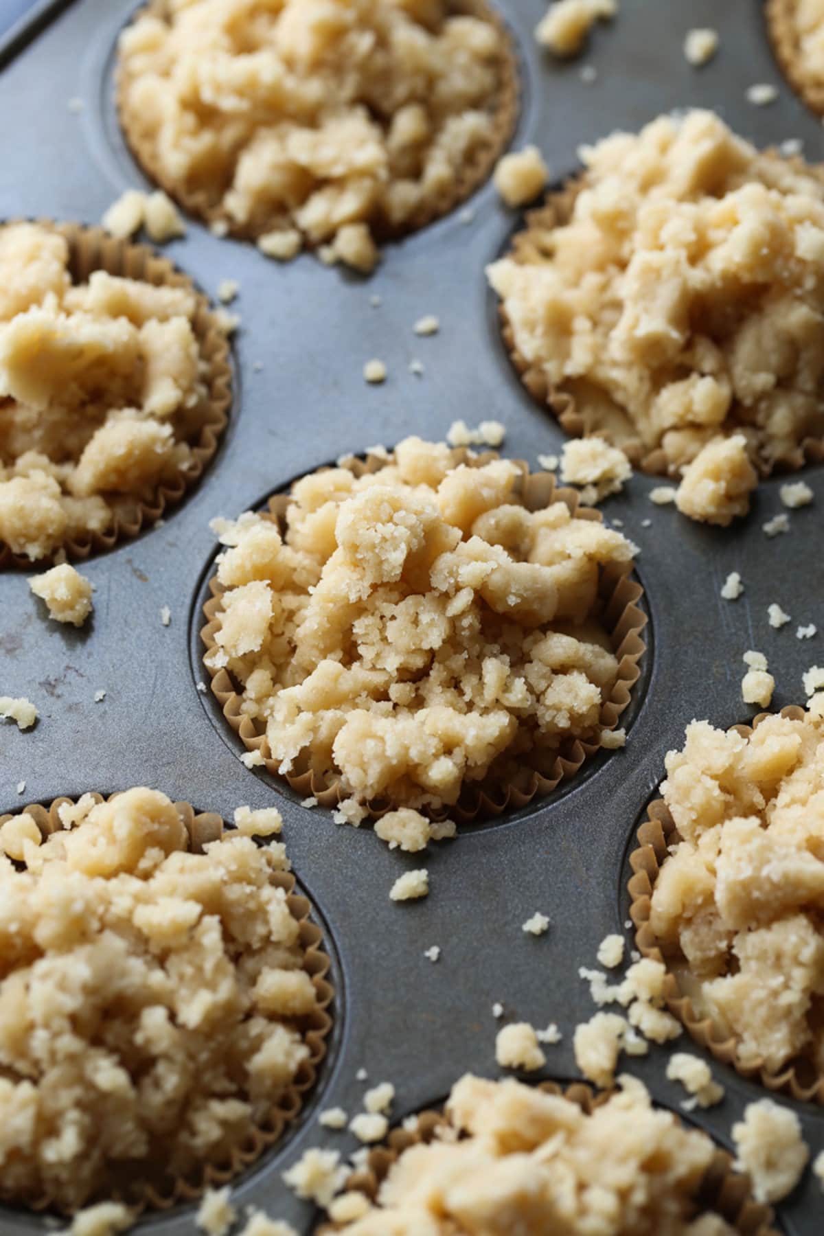 cobertura de migas en muffins de plátano antes de hornearlos en un molde para muffins