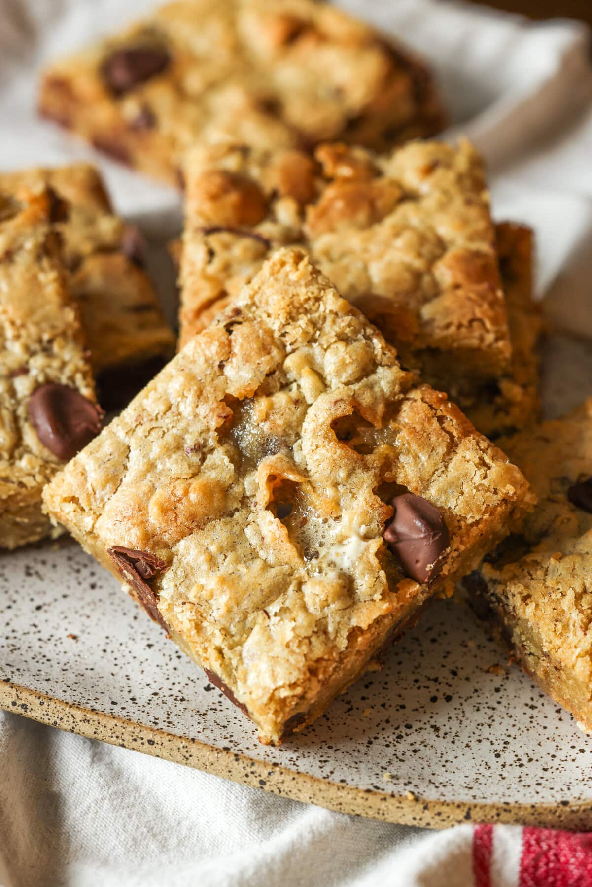 Mi Receta Blondie es la perfección. Barras de galletas masticables y mantecosas tachonadas con chispas de chocolate y mezcladas con coco dulce. Barras de galletas Blondie cortadas en cuadrados en un plato