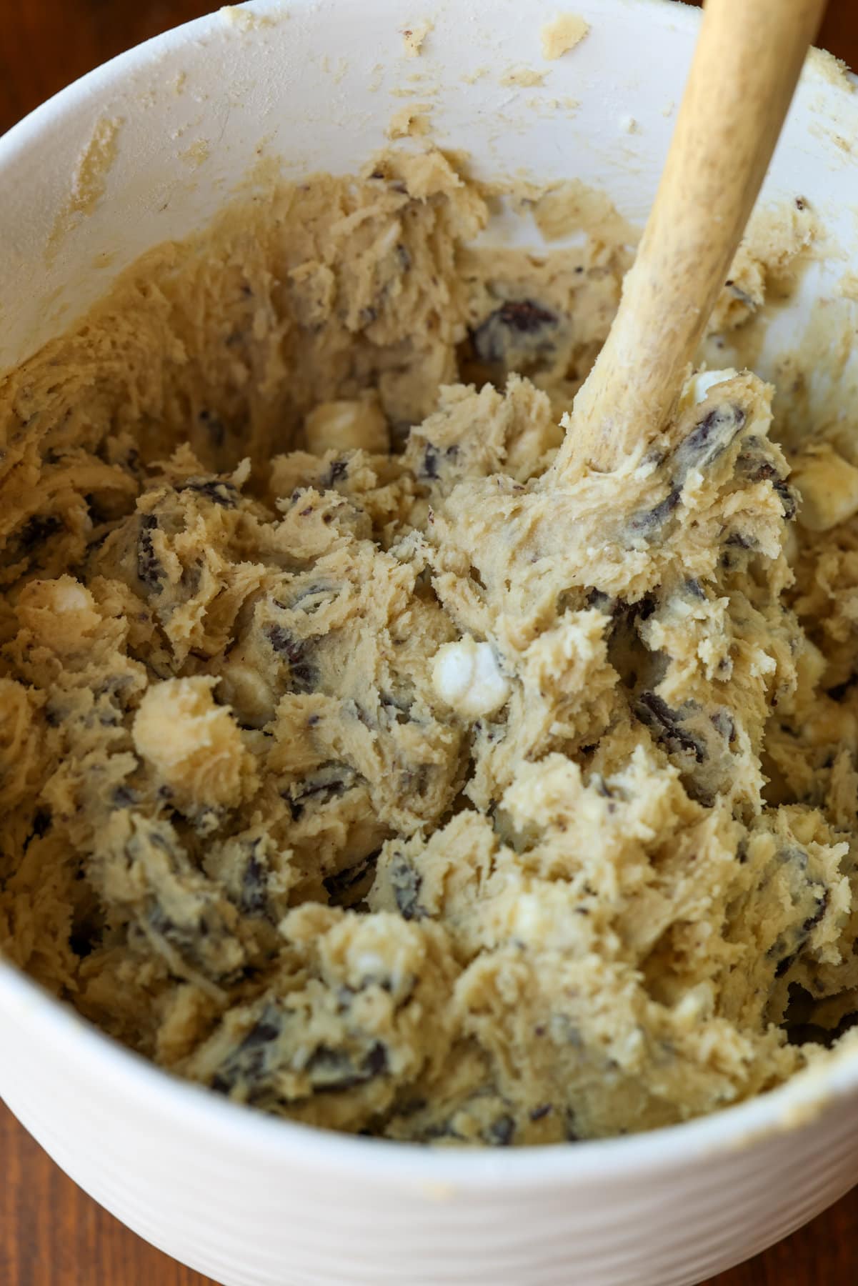 Mi Receta Blondie es la perfección. Barras de galletas masticables y mantecosas tachonadas con chispas de chocolate y mezcladas con coco dulce. Receta de blondie masa para galletas en una cuenco de cerámica blanca