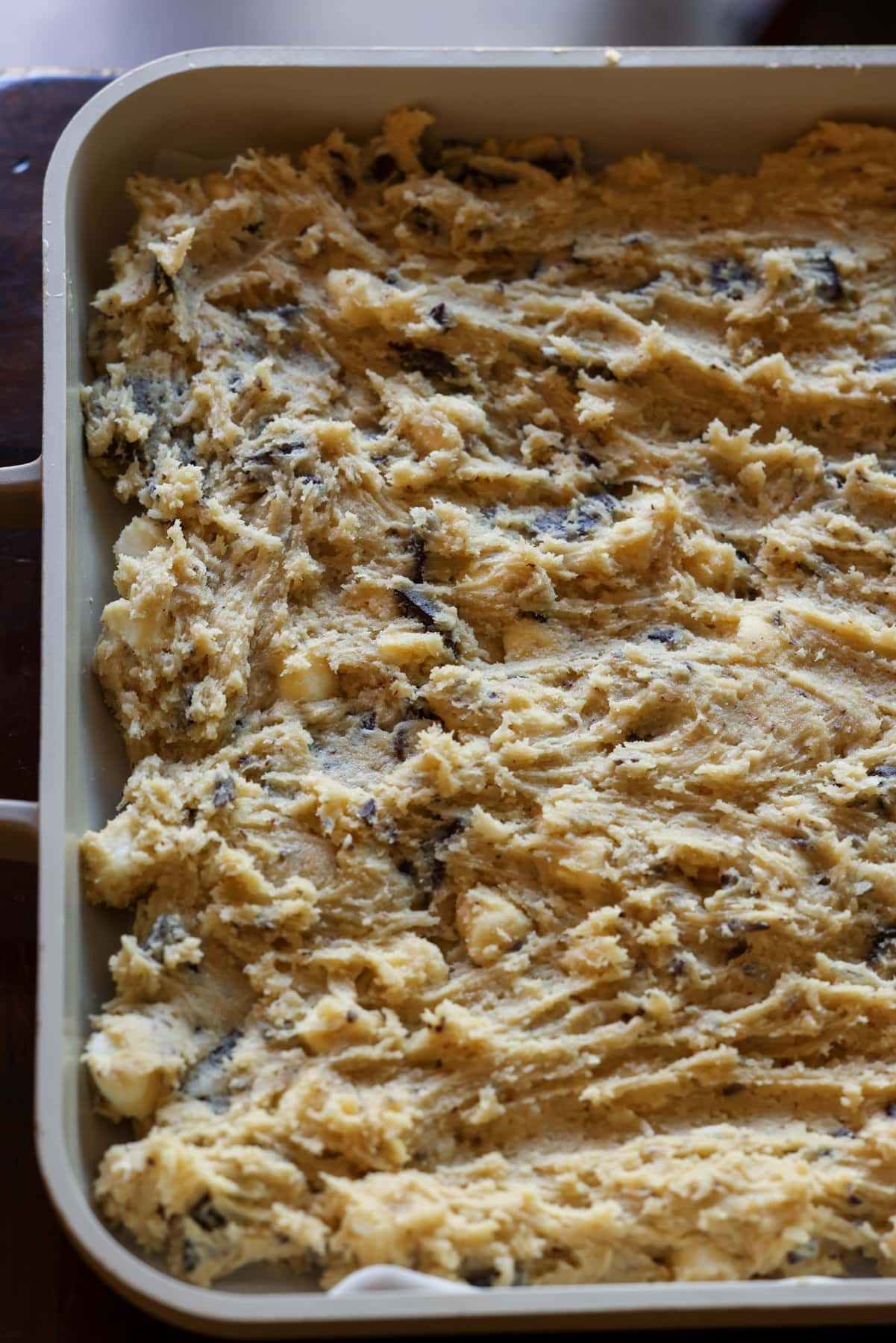 Mi Receta Blondie es la perfección. Barras de galletas masticables y mantecosas tachonadas con chispas de chocolate y mezcladas con coco dulce. Masa para galletas Blondie prensada en una fuente para horno grande