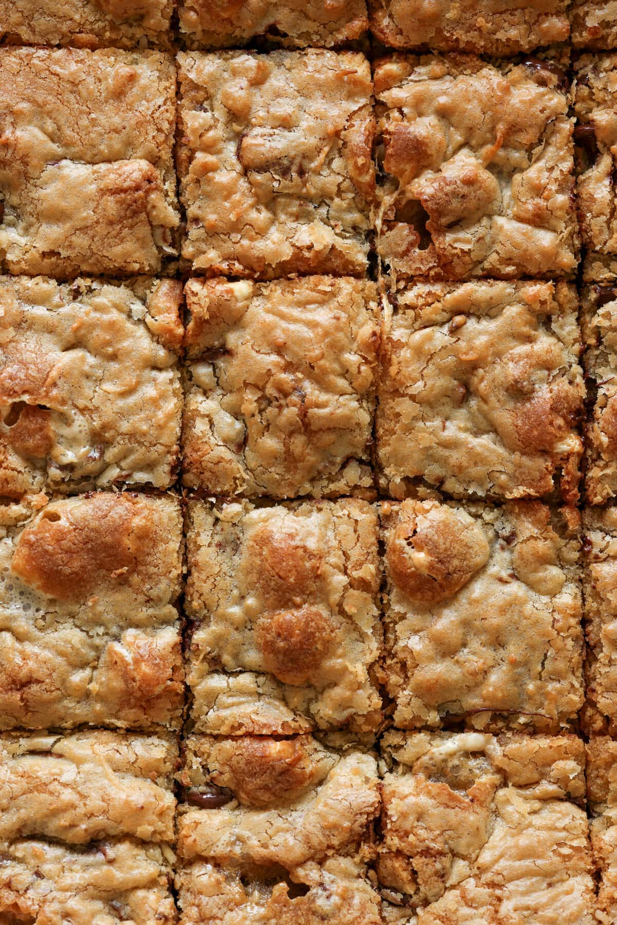 Mi Receta Blondie es la perfección. Barras de galletas masticables y mantecosas tachonadas con chispas de chocolate y mezcladas con coco dulce. Receta de Blondies horneada en una fuente para horno grande cortada en cuadrados desde arriba