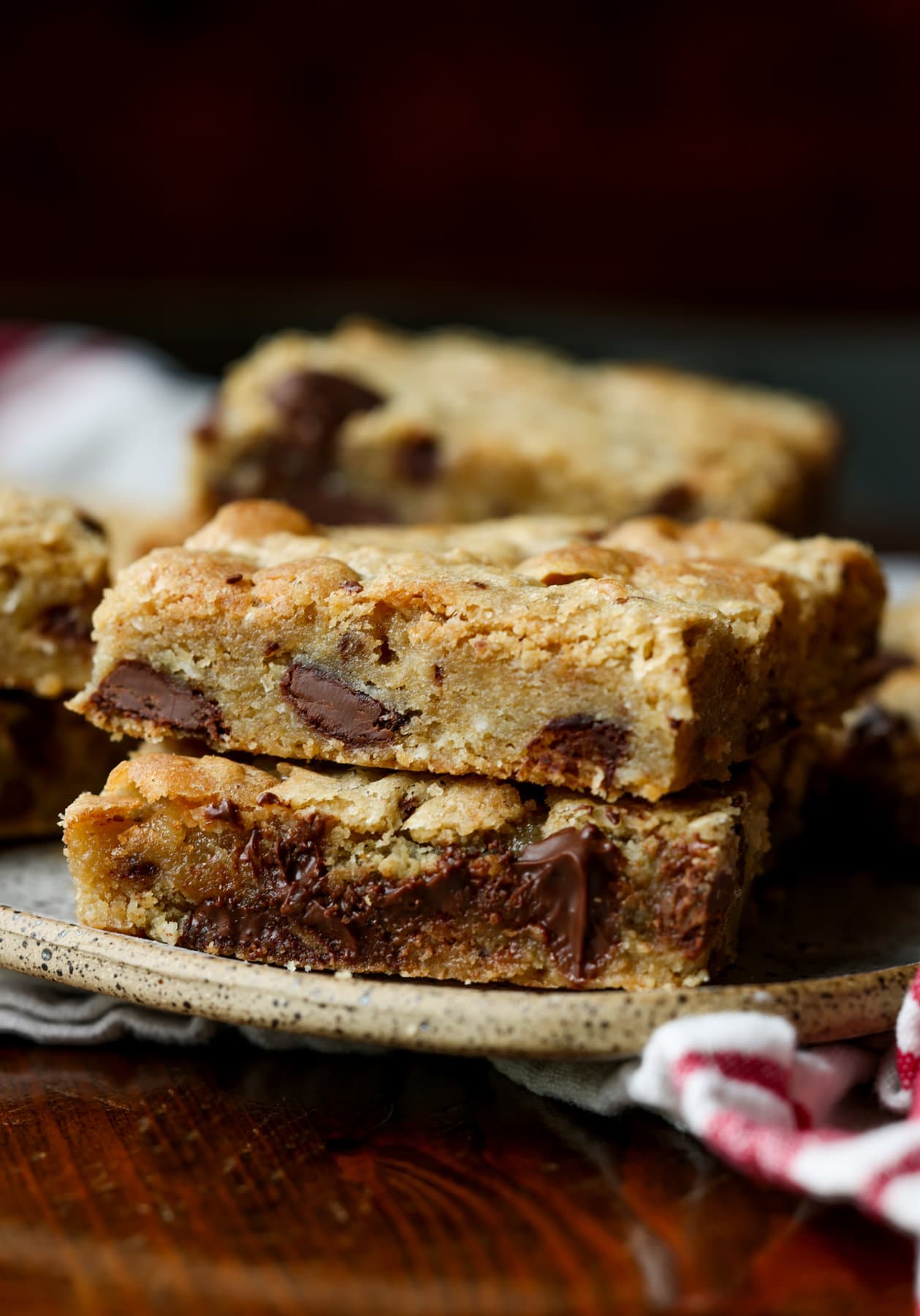 Mi Receta Blondie es la perfección. Barras de galletas masticables y mantecosas tachonadas con chispas de chocolate y mezcladas con coco dulce. Dos blondies apilados en un plato con trozos de chocolate