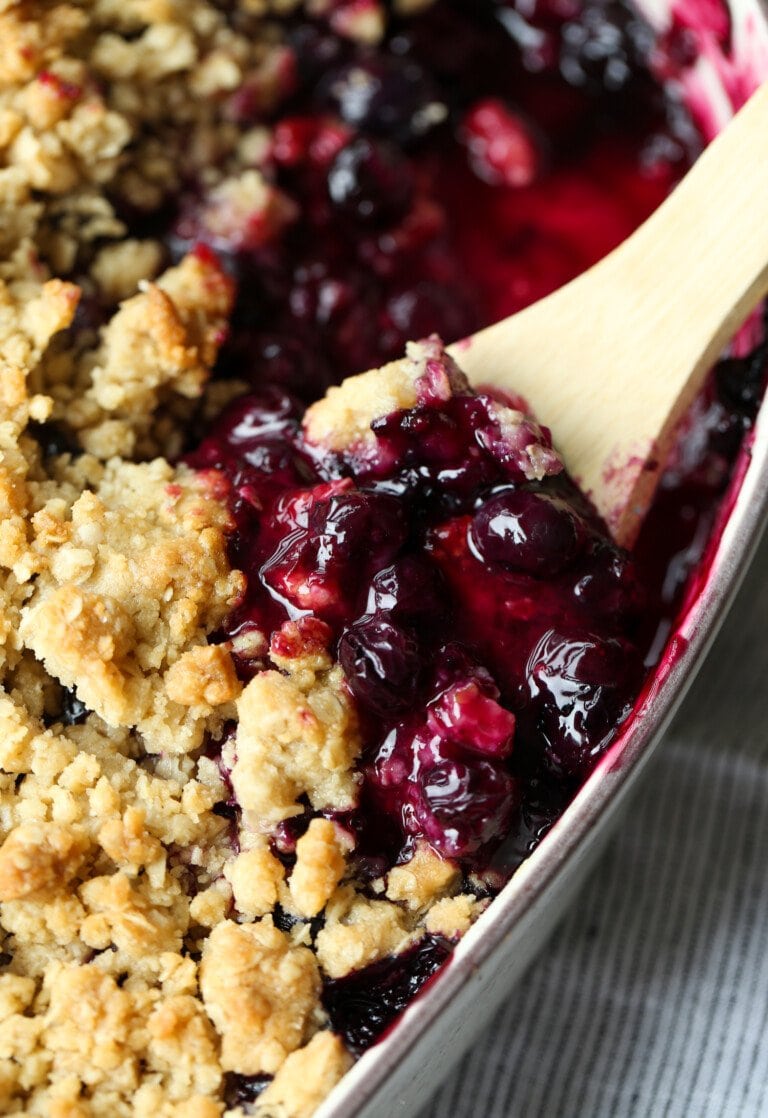 Blueberry Crisp en una fuente para horno con una cuchara para servir