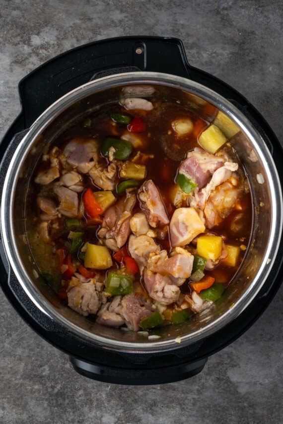 Instant Pot Hawaiian Chicken es una cena fácil de una olla cocinada con piña jugosa, pimientos y cebollas en una salsa dulce y picante. Ingredientes de pollo hawaiano combinados dentro de Instant Pot.