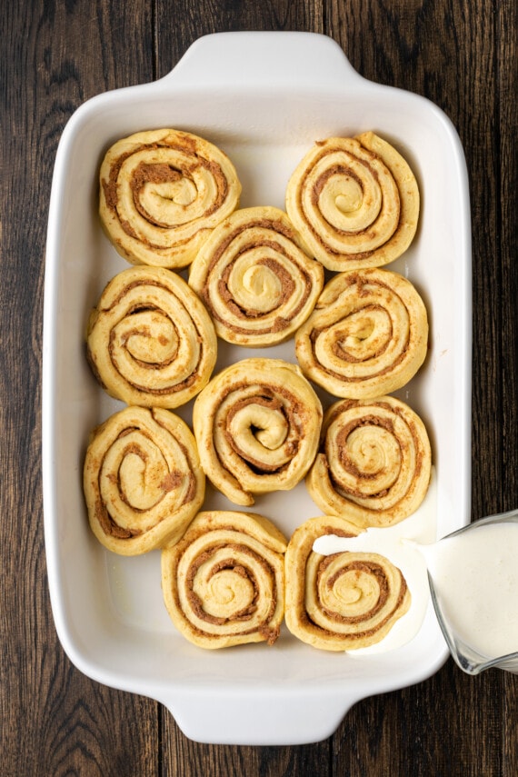 Make the viral TikTok cinnamon rolls with heavy cream! These easy cinnamon rolls taste homemade, perfect as a sweet breakfast or easy dessert. Heavy cream is poured over unbaked Grands cinnamon rolls in a white ceramic baking dish.