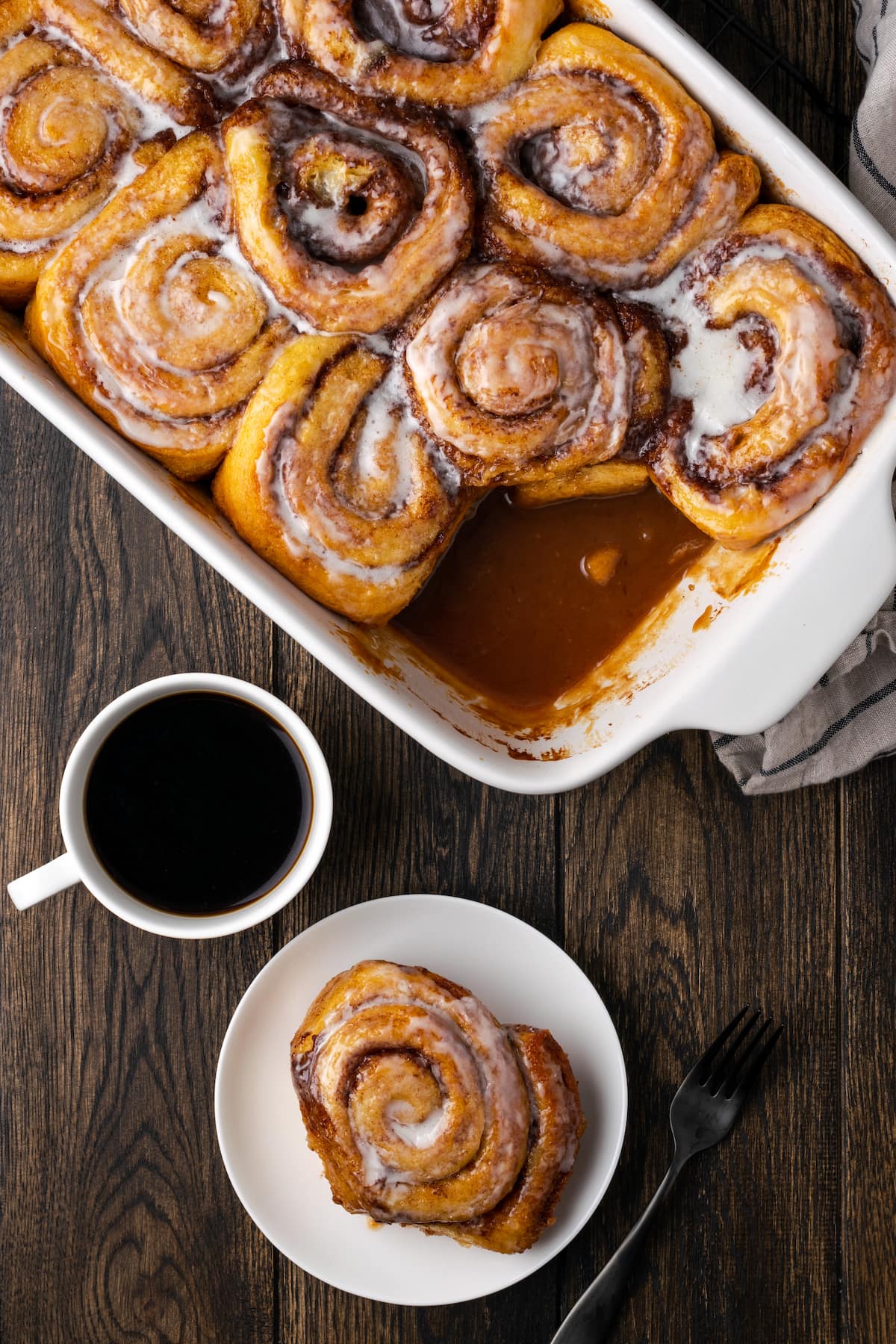 Make the viral TikTok cinnamon rolls with heavy cream! These easy cinnamon rolls taste homemade, perfect as a sweet breakfast or easy dessert. Overhead view of cinnamon rolls in a baking dish, next to one cinnamon roll served on a plate next to a cup of coffee.