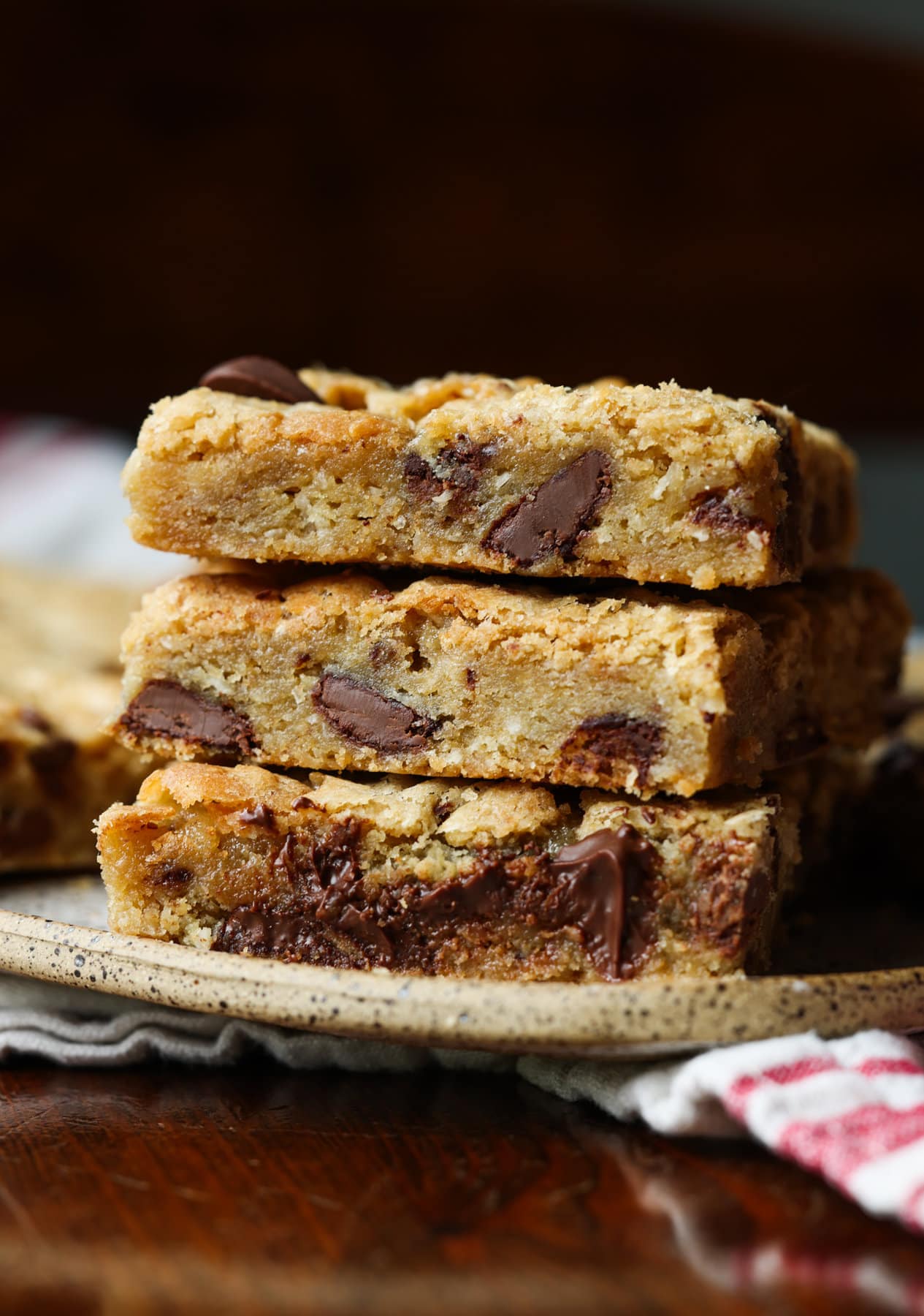 Mi Receta Blondie es la perfección. Barras de galletas masticables y mantecosas tachonadas con chispas de chocolate y mezcladas con coco dulce. 3 barras de galletas rubias apiladas en un plato