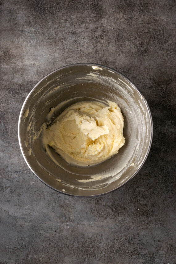 Cream cheese, butter, and sugar creamed together in a metal mixing bowl.