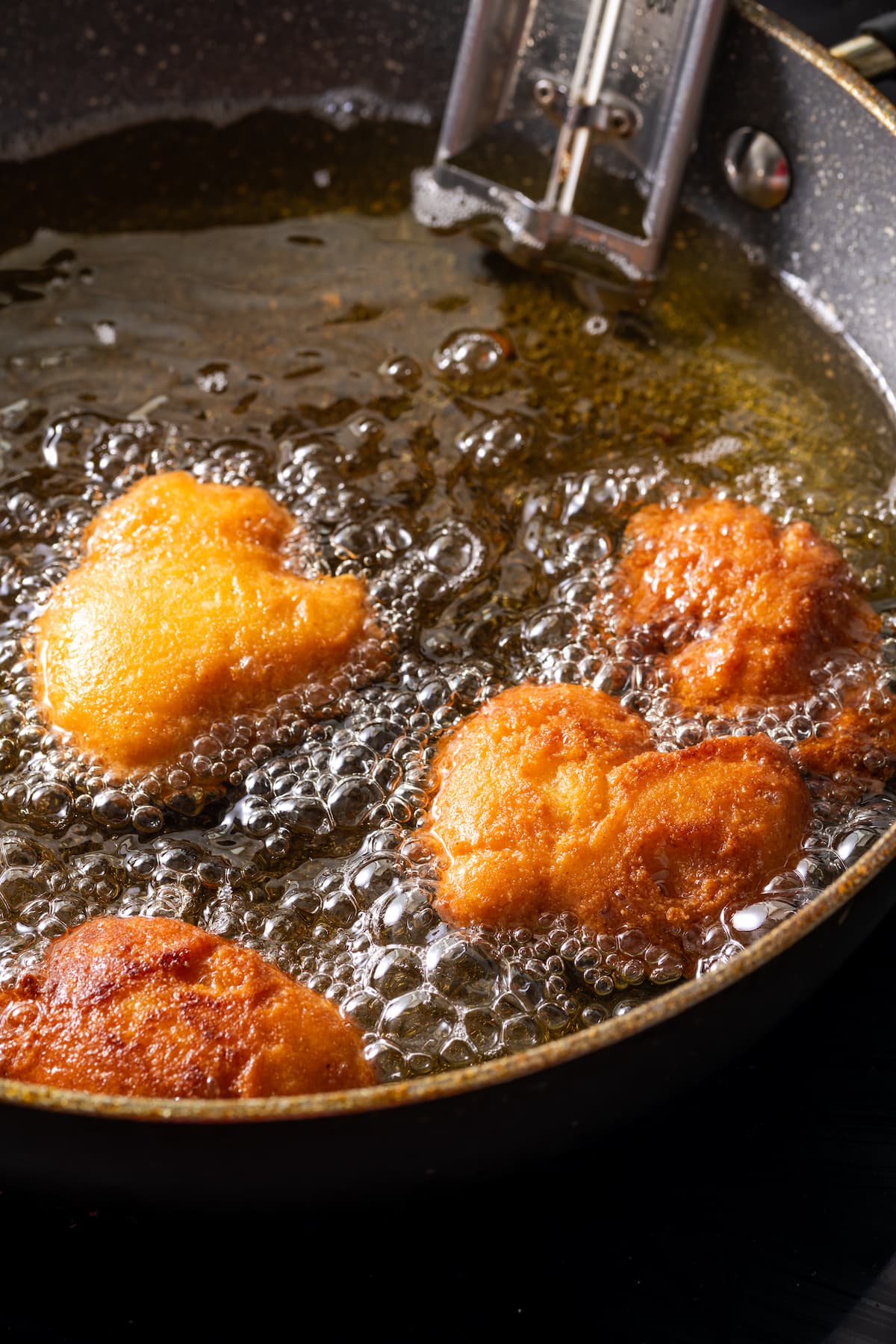 Crispy hot water cornbread is totally crave-worthy! Fried cornbread is an easy side dish to pair with your favorite Southern meals. Hot water cornbread fritters deep-frying in a skillet.