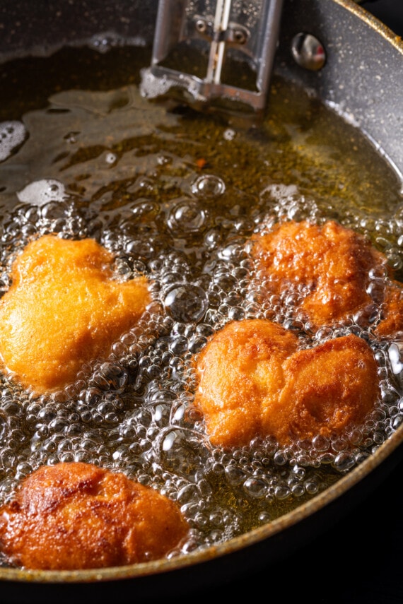 Crispy hot water cornbread is totally crave-worthy! Fried cornbread is an easy side dish to pair with your favorite Southern meals. Hot water cornbread fritters deep-frying in a skillet.