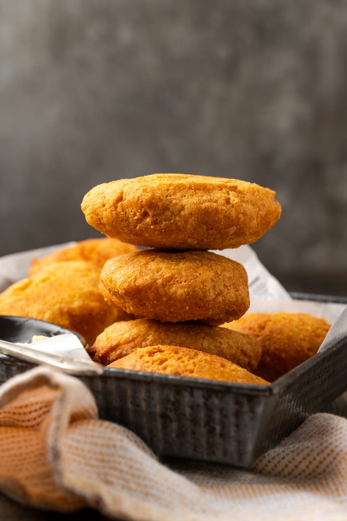 Crispy hot water cornbread is totally crave-worthy! Fried cornbread is an easy side dish to pair with your favorite Southern meals. Side view of a stack of hot water cornbread in a basket.