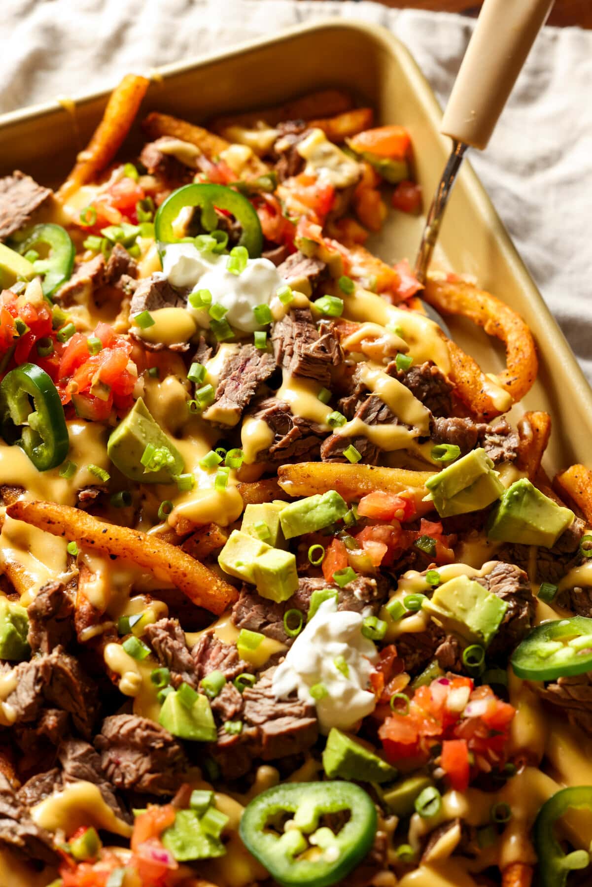 Carne Asada Fries Are a Tex Mex spin on loaded french fries. Marinated, grilled carne asada is sliced and served on top of seasoned fries with a cheesy sauce and all the toppings of your choice! French fries topped with Carne Asada, cheese, avocado, and sour cream