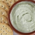 Crackers next to a creamy green dip.