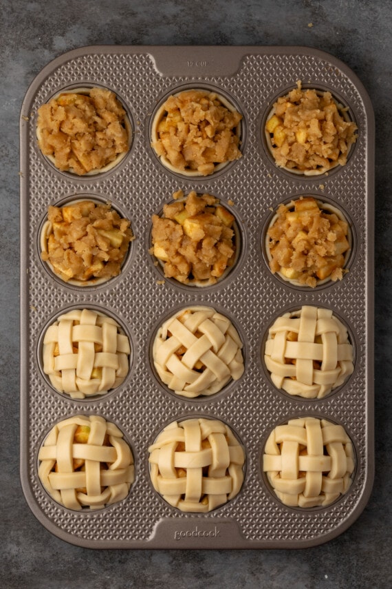 Mini apple pies are a bite-sized spin on a classic fall dessert! So easy to make and bursting with juicy apple pie filling and warm spices. Partially assembled mini apple pies in a 12-well muffin tin.