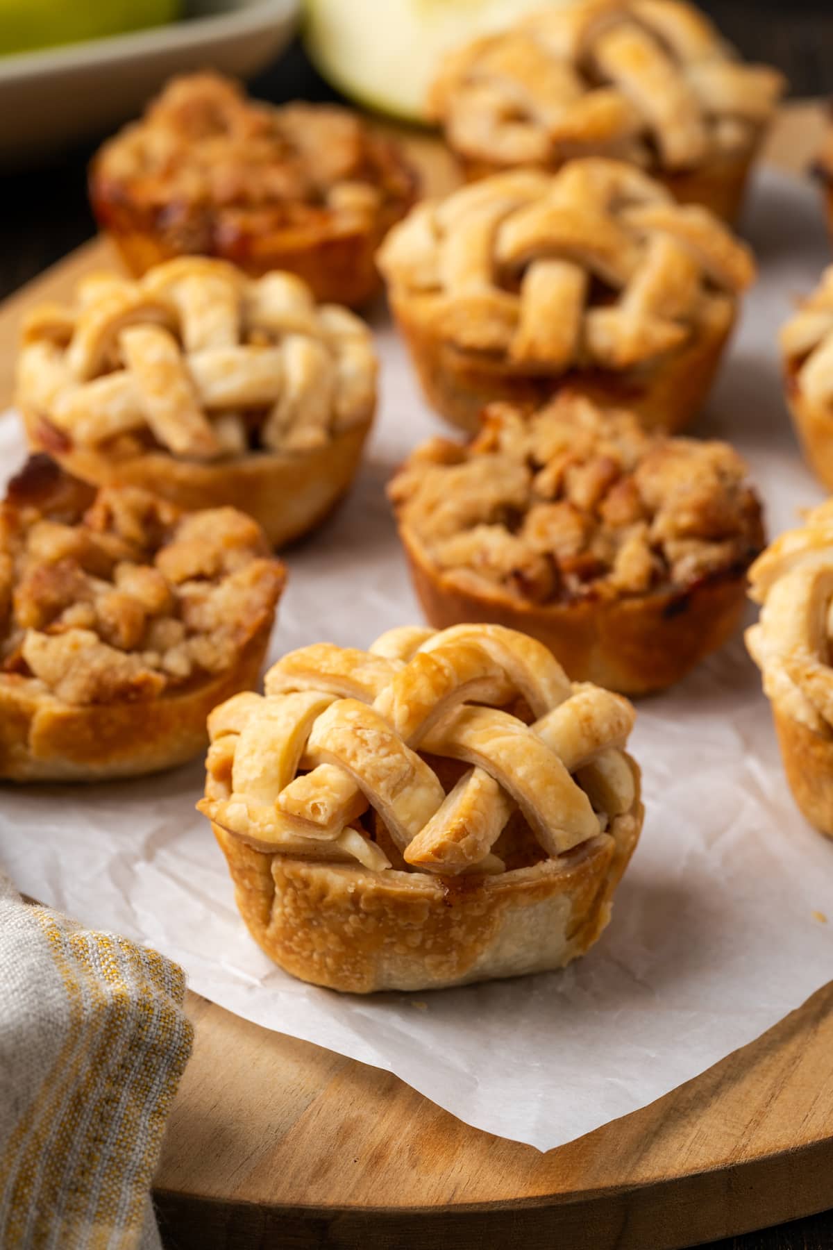 Mini apple pies are a bite-sized spin on a classic fall dessert! So easy to make and bursting with juicy apple pie filling and warm spices. Mini apple pies on a piece of parchment paper.