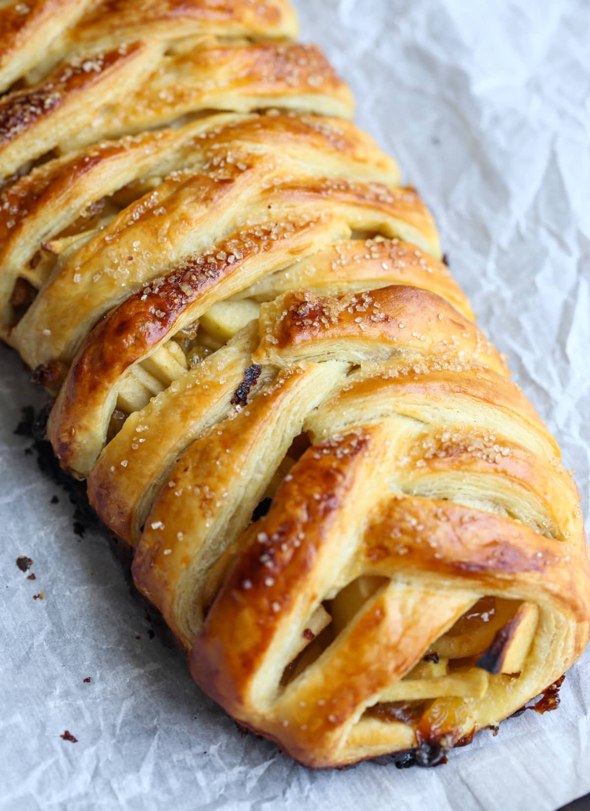 This easy Apple Strudel recipe is filled with cinnamon, brown sugar, raisins and more! It's a crispy, flaky pastry that's easy to make and downright delicious. A baked apple strudel with a braided pastry on a baking sheet