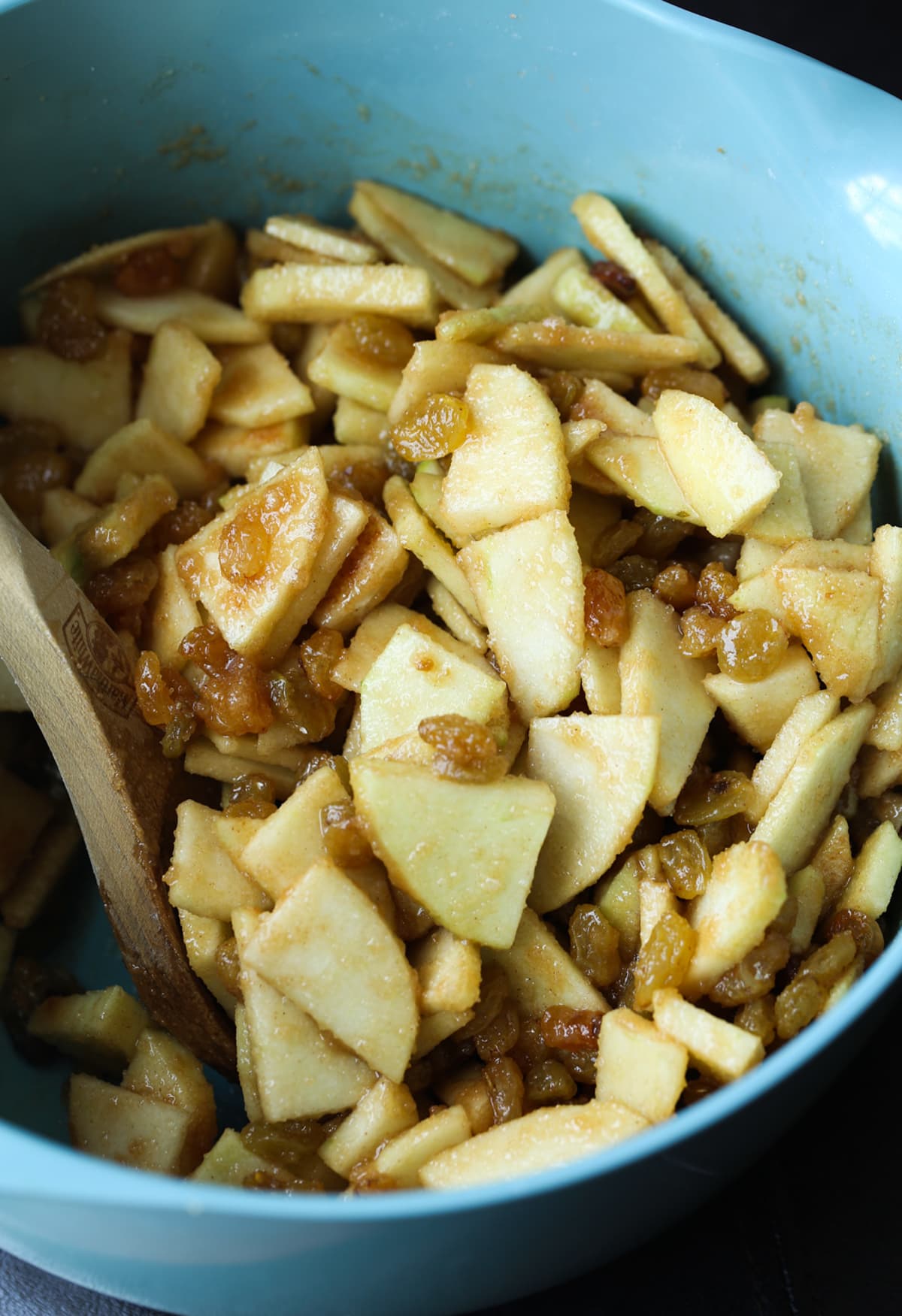 This easy Apple Strudel is filled with cinnamon, brown sugar, raisins and more! It's a crispy, flaky pastry that's easy to make and downright delicious. A blue bowl filled with chopped sliced apples coated in cinnamon sugar