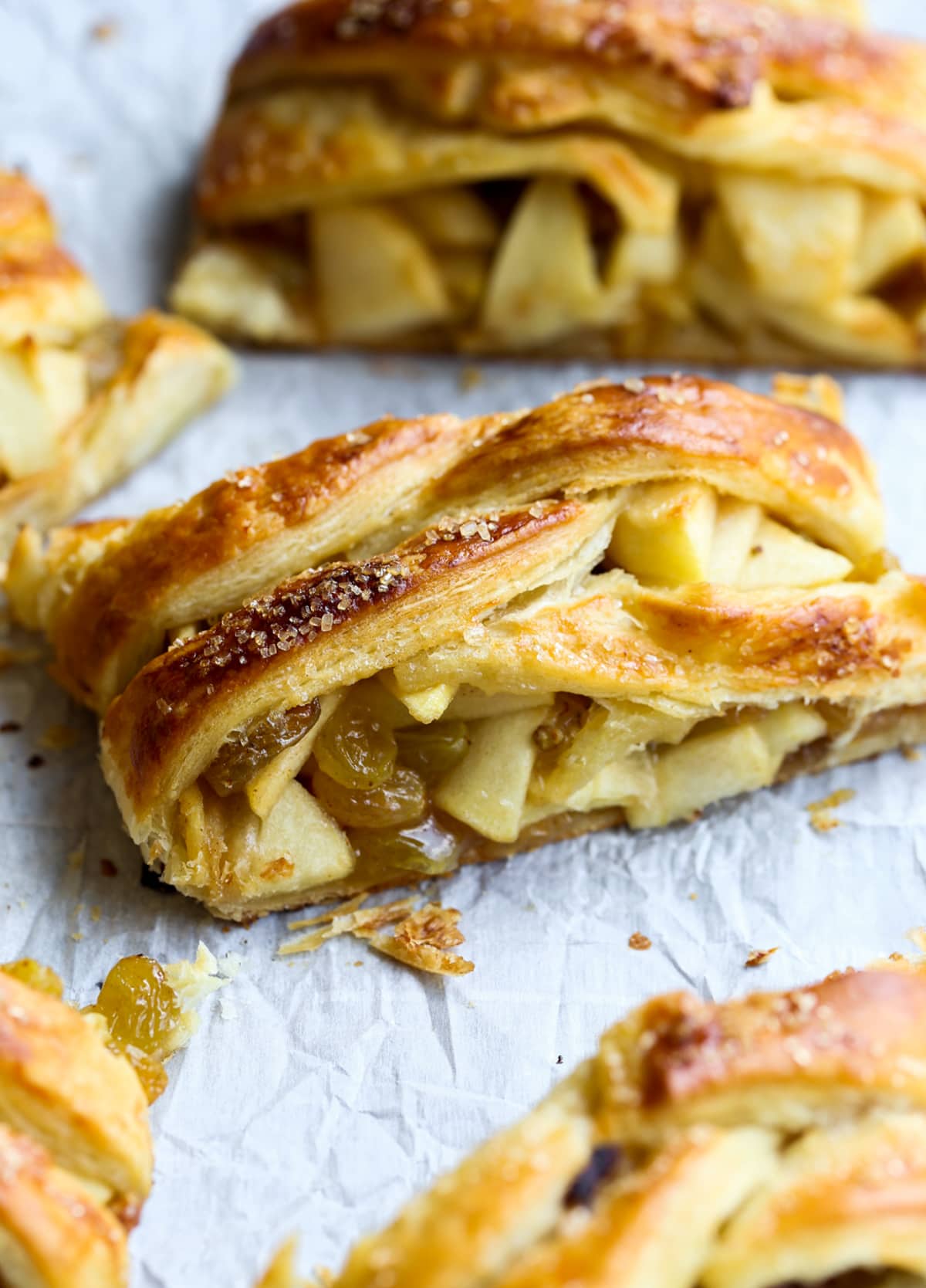 This easy Apple Strudel is filled with cinnamon, brown sugar, raisins and more! It's a crispy, flaky pastry that's easy to make and downright delicious. A slice of apple strudel on a parchment lined baking sheet