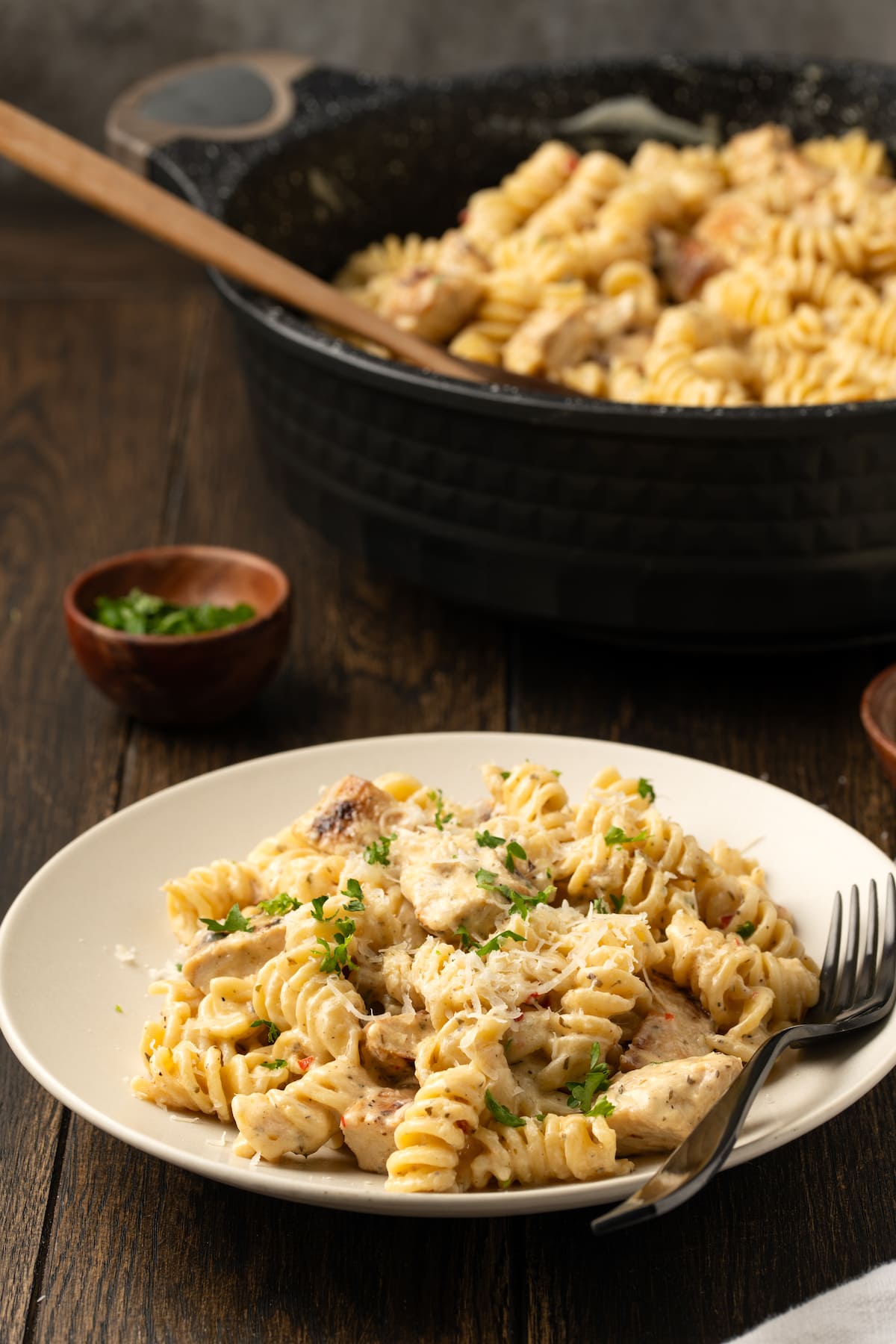 Creamy Buffalo Wild Wings Garlic Parmesan Chicken Pasta is a quick and easy dinner idea packed with bold flavor. Made with only 6 ingredients! A bowl of Buffalo Wild Wings garlic parmesan chicken pasta next to a skillet.