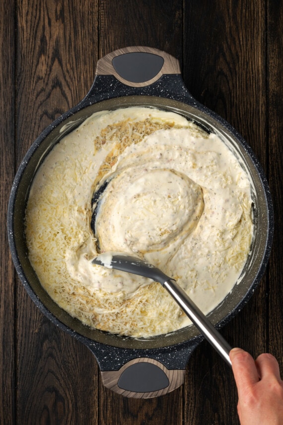 Creamy Buffalo Wild Wings Garlic Parmesan Chicken Pasta is a quick and easy dinner idea packed with bold flavor. Made with only 6 ingredients! The ingredients for buffalo garlic parmesan pasta sauce stirred together in a skillet.