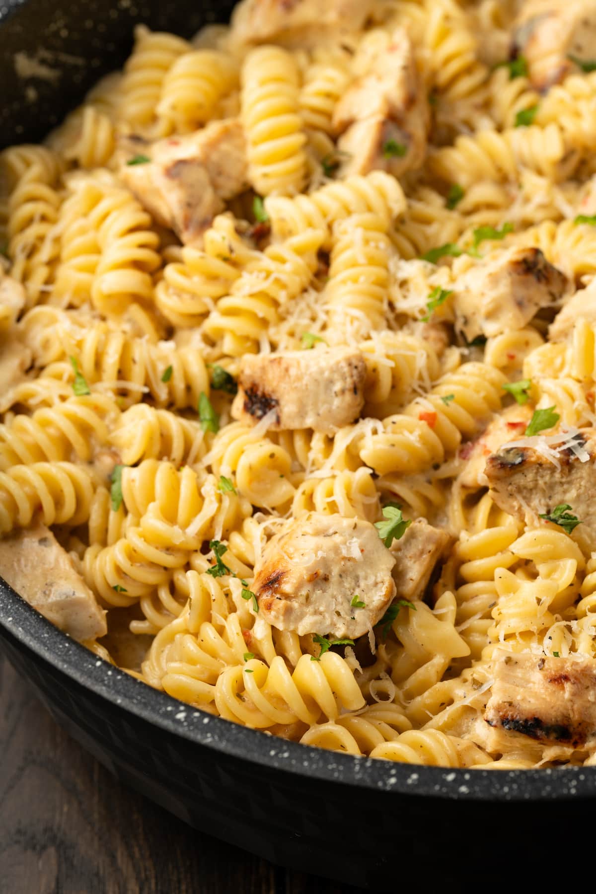 Creamy Buffalo Wild Wings Garlic Parmesan Chicken Pasta is a quick and easy dinner idea packed with bold flavor. Made with only 6 ingredients! Close up of Buffalo Wild Wings garlic parmesan chicken pasta in a skillet.