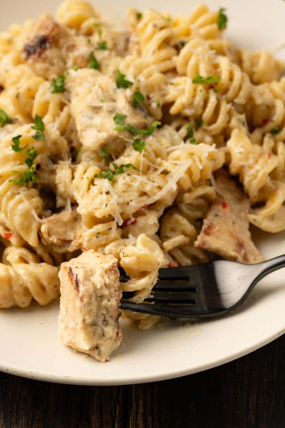 Creamy Buffalo Wild Wings Garlic Parmesan Chicken Pasta is a quick and easy dinner idea packed with bold flavor. Made with only 6 ingredients! Close up of a bowl of Buffalo Wild Wings garlic parmesan chicken pasta with a fork.
