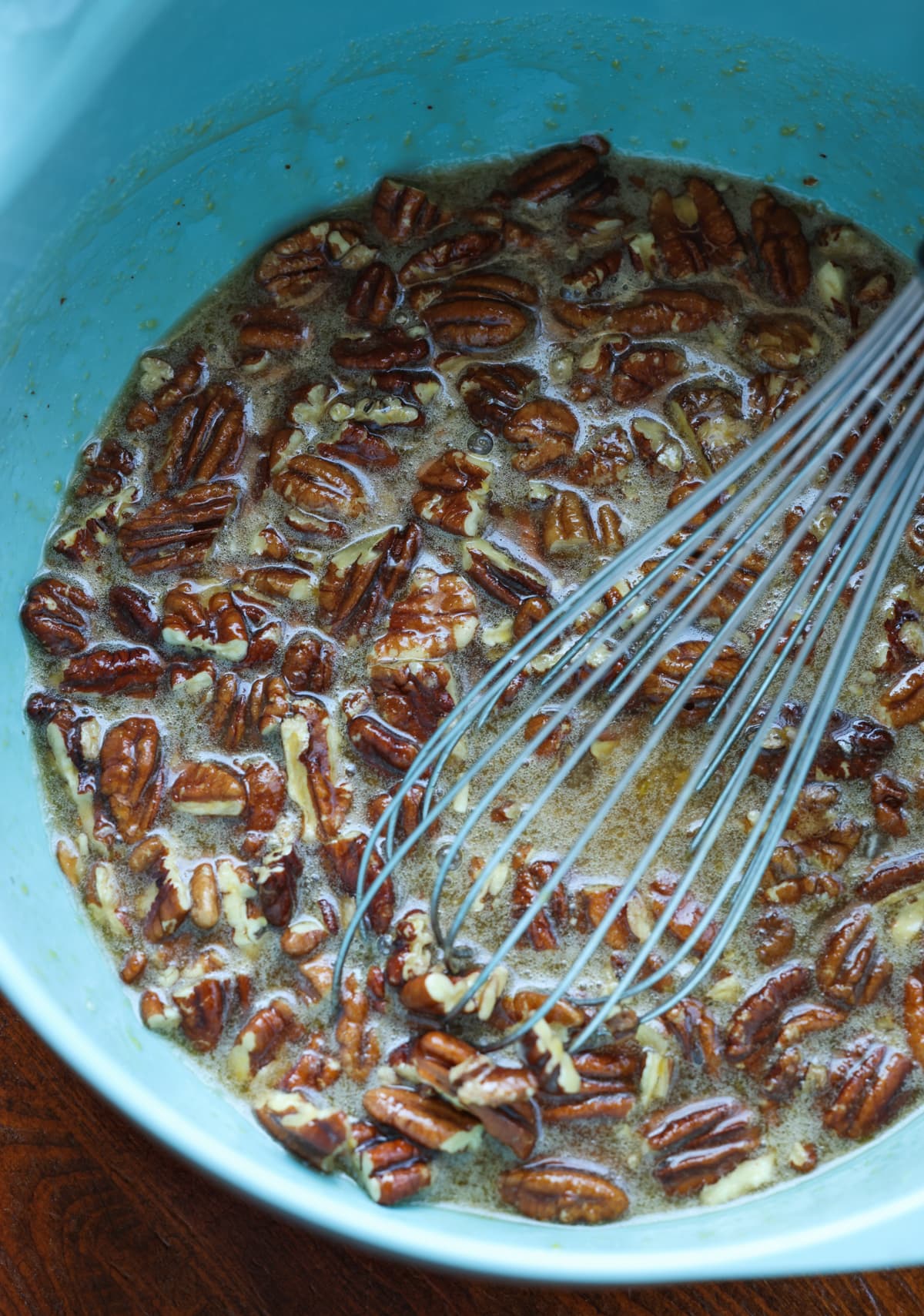 Pecan tart mixture in a blue bowl with a whisk