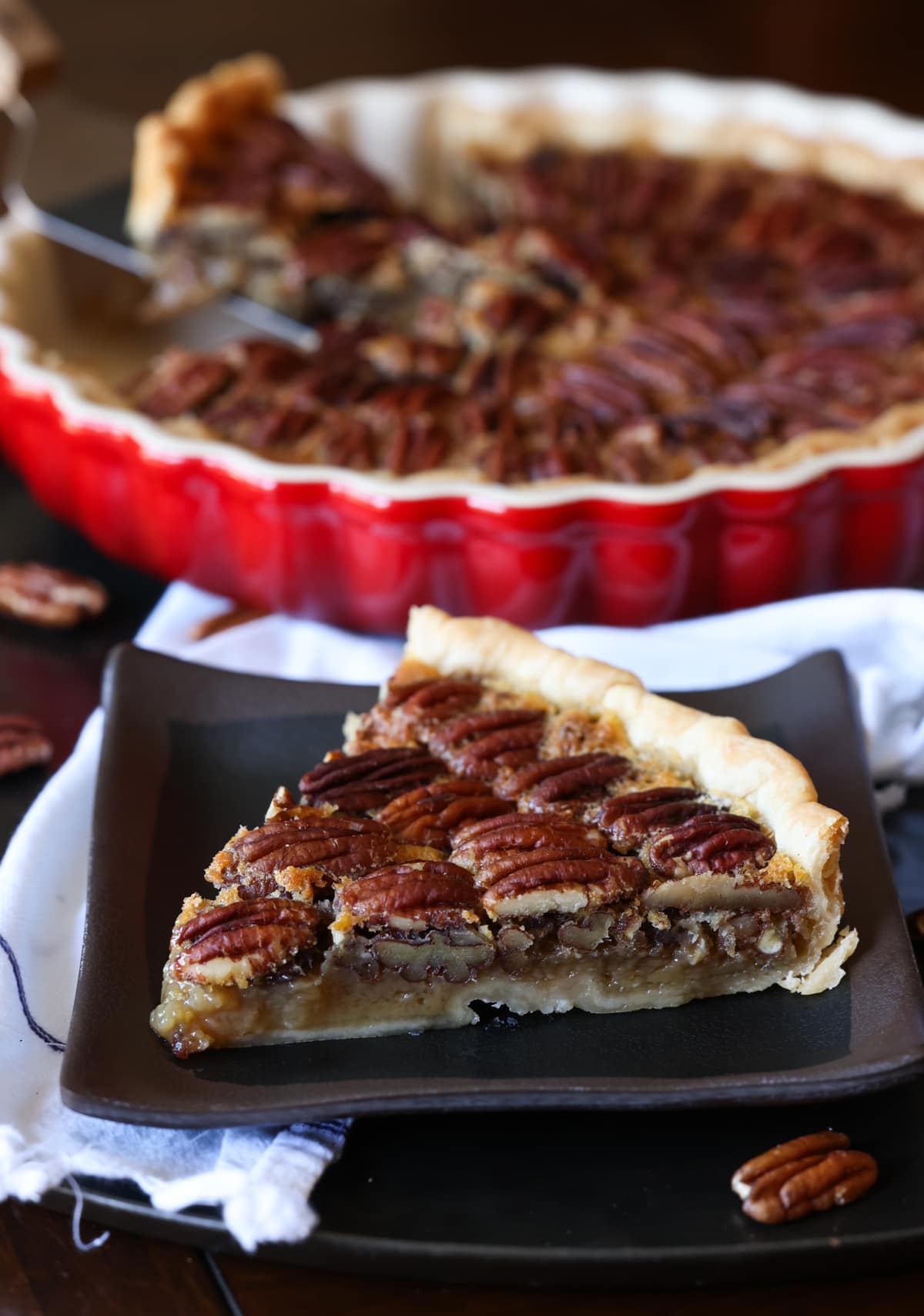 A pecan tart slice on a black plate