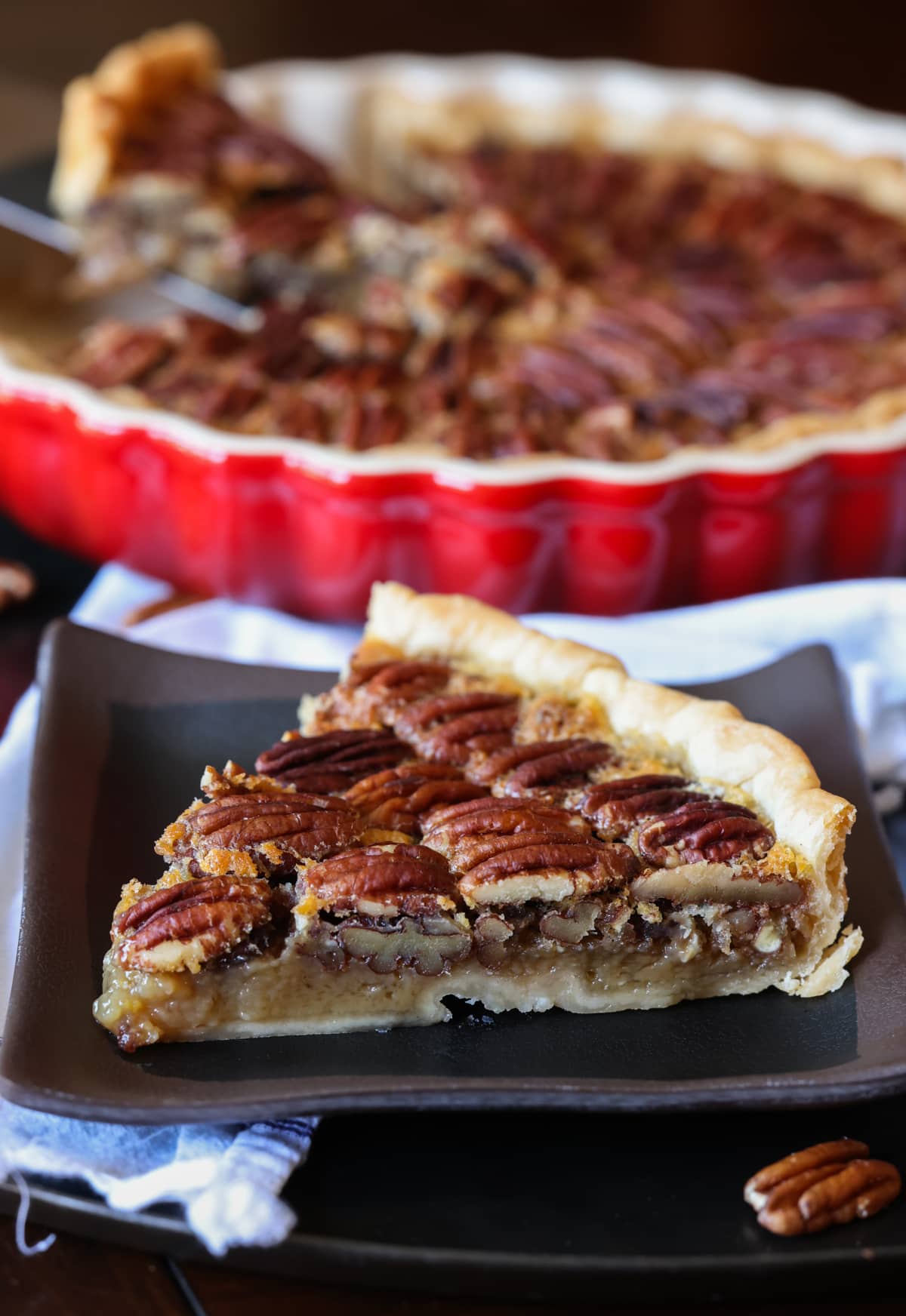 Pecan Tart slice on a black plate in front of a tart pan