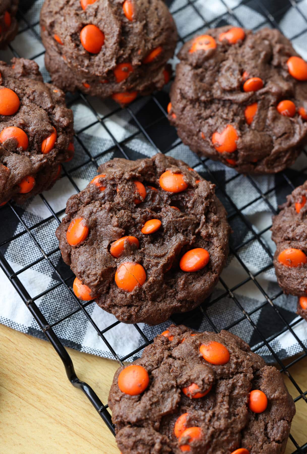 This dark chocolate cookies recipe combines the richness of dark chocolate with texture that is brownie-like, filled with chocolate candy! Chocolate Brownie Cookies on a wire rack filled with orange M&Ms