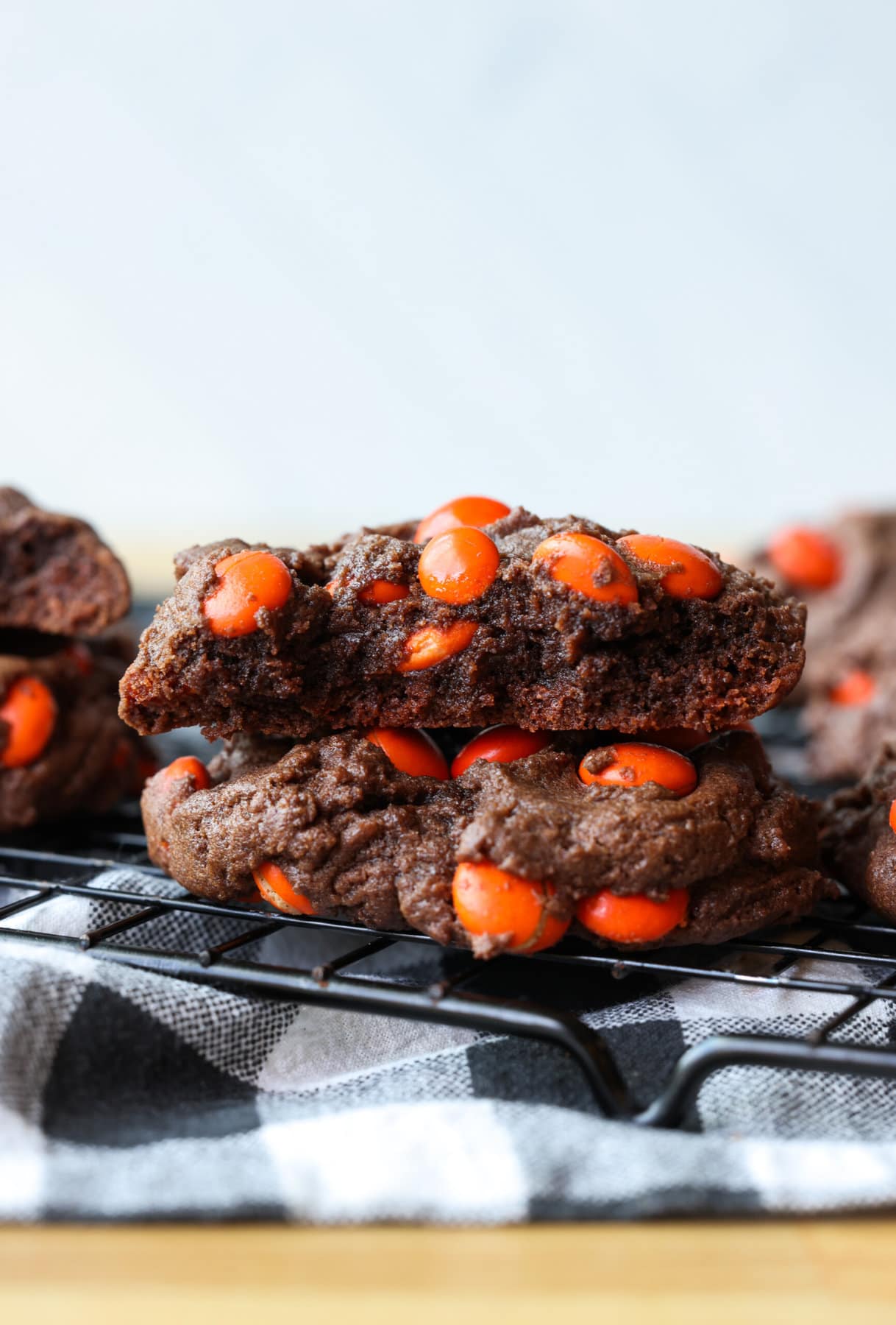 This dark chocolate cookies recipe combines the richness of dark chocolate with texture that is brownie-like, filled with chocolate candy! Two chocolate cookies with M&Ms stacked and the top one broken in half showing the fudgy interior