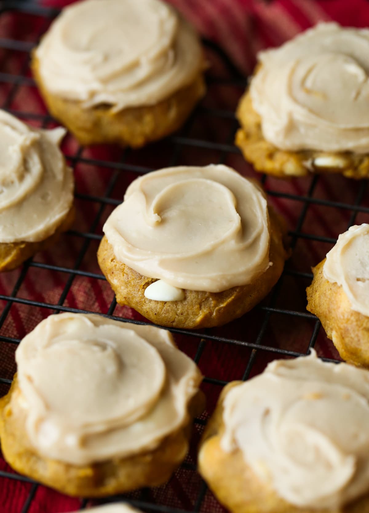 pumpkin cookies with white chocolate chips and icing on a cooling rack
