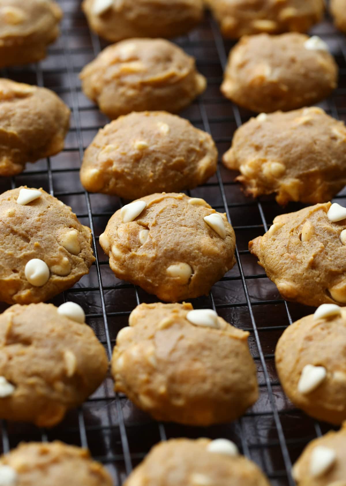 Pumpkin cookies cooling on a wire rack before spreading with iciing.
