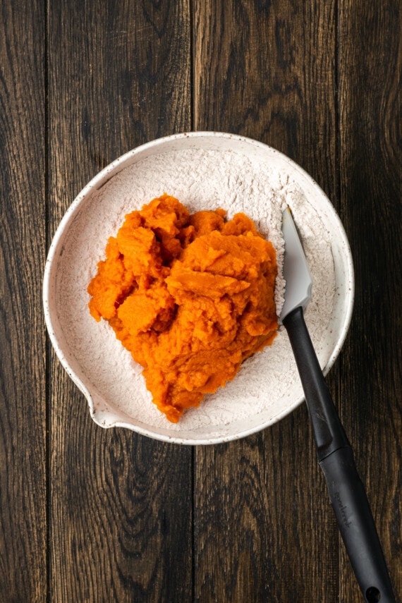 These soft and fluffy pumpkin cookies with cake mix are an easy fall dessert, made with only 2 ingredients and ready for the oven in minutes! Canned pumpkin added to a mixing bowl with spice cake mix.
