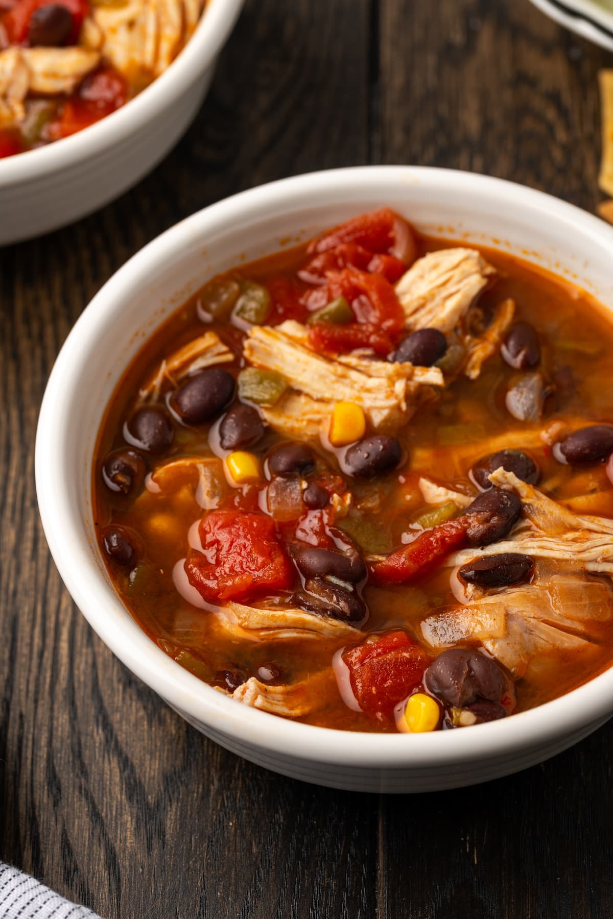 Smoky and flavorful Instant Pot chicken tortilla soup is a comforting one-pot meal that's easy to make any night of the week! Close up of a bowl of Instant Pot chicken tortilla soup on a wooden countertop.