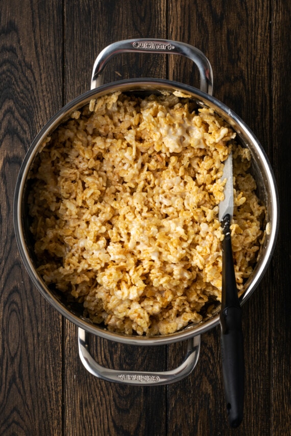 Rice Krispies cereal combined with melted marshmallow mixture in a saucepan.