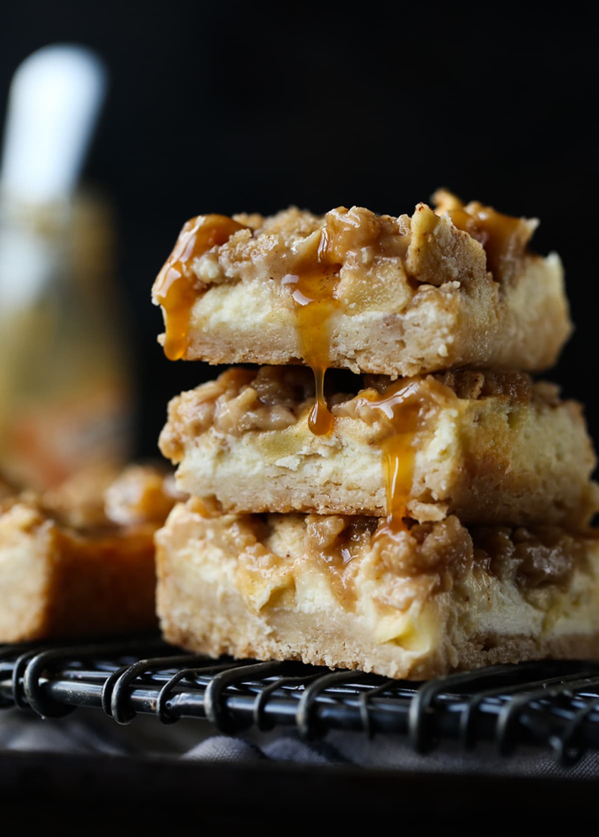 Caramel Apple Cheesecake Bars are creamy, sweet and delicious. They're a simple, buttery crust with an easy apple cheesecake filling topped with an oat streusel and caramel. Caramel Apple Cheesecake Bars stacked with caramel dropping down