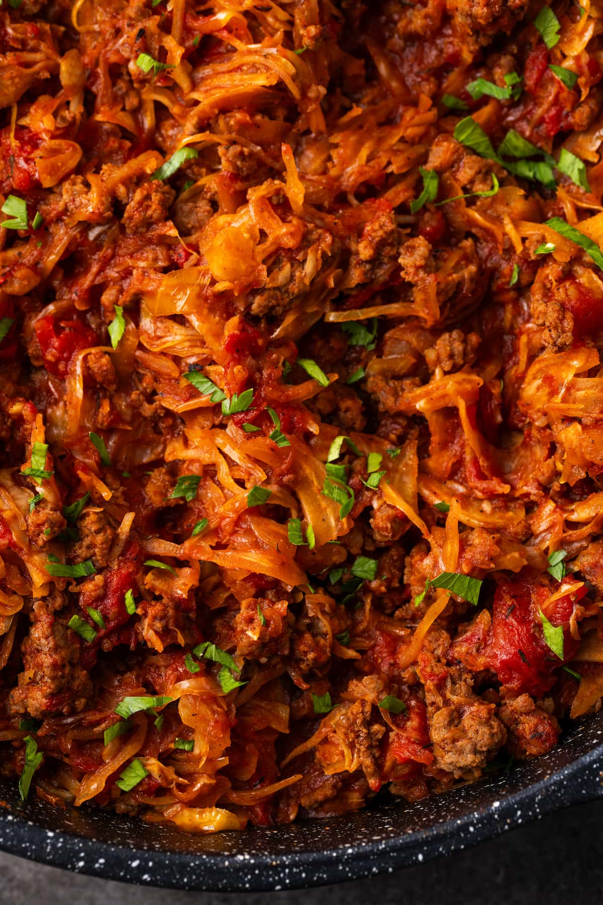 This easy unstuffed cabbage recipe is a savory one-pot meal made with juicy ground beef, pork, tangy fire-roasted tomatoes, and onions. Close up of unstuffed cabbage in a skillet.