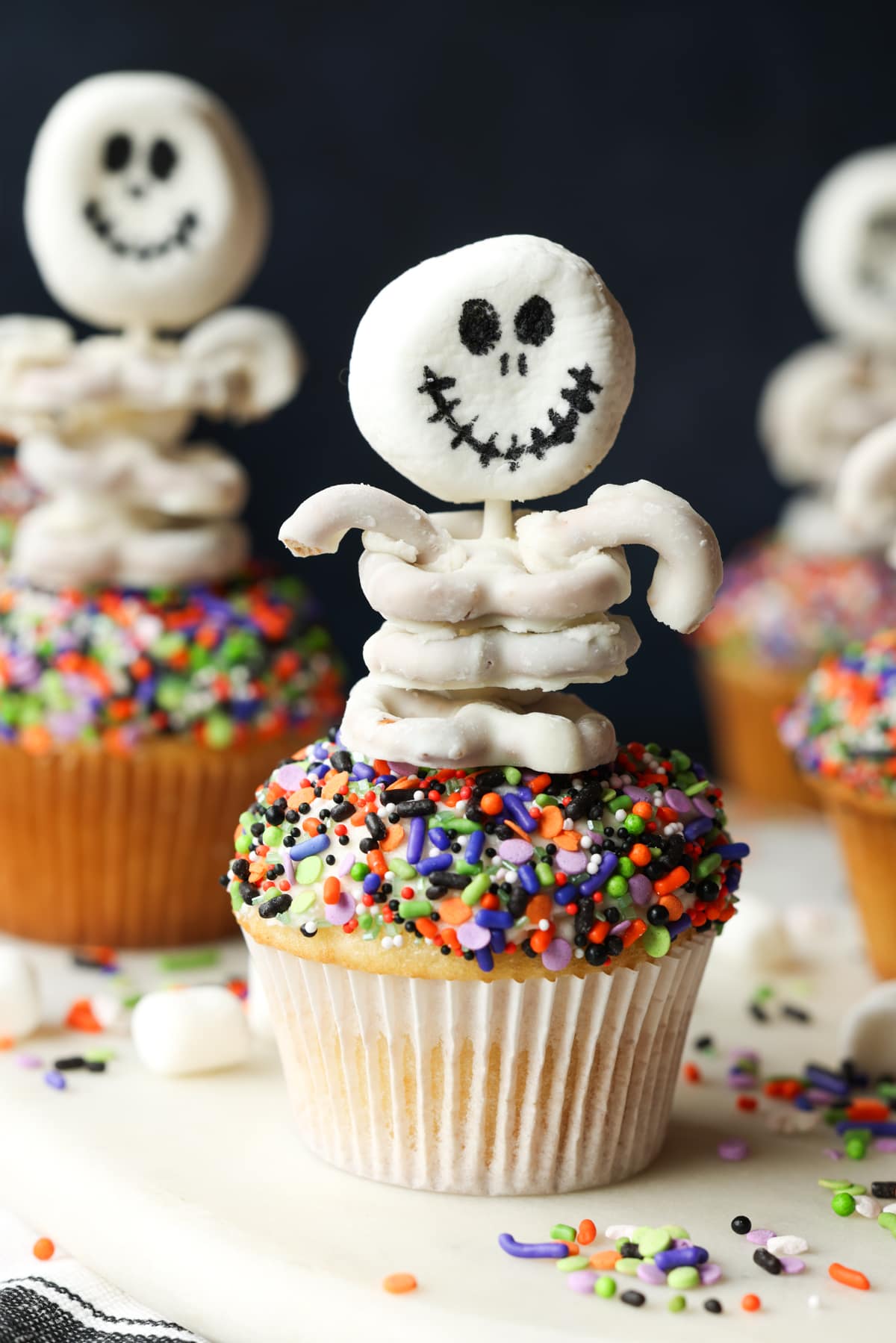 These are adorable Skeleton Halloween Cupcakes that are perfect for spooky season! Easy to make and so cute for classroom parties and a fun activity to do with your kids! A halloween cupcake topped with a skeleton made from marshmallows and white chocolate covered pretzels
