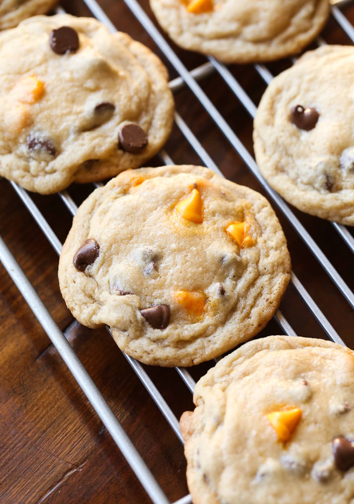 Baked cookies on a wire cooking rack with orange and chocolate chips